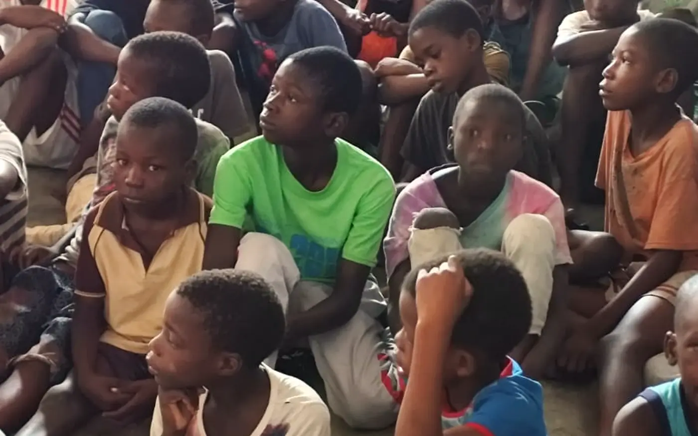 Grupo de crianças e adolescentes sentados no chão, atentos